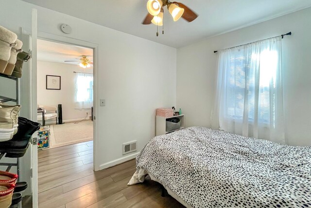 bedroom with visible vents, baseboards, wood finished floors, and a ceiling fan