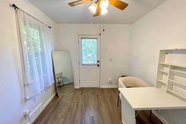 doorway with visible vents, baseboards, a ceiling fan, and wood finished floors