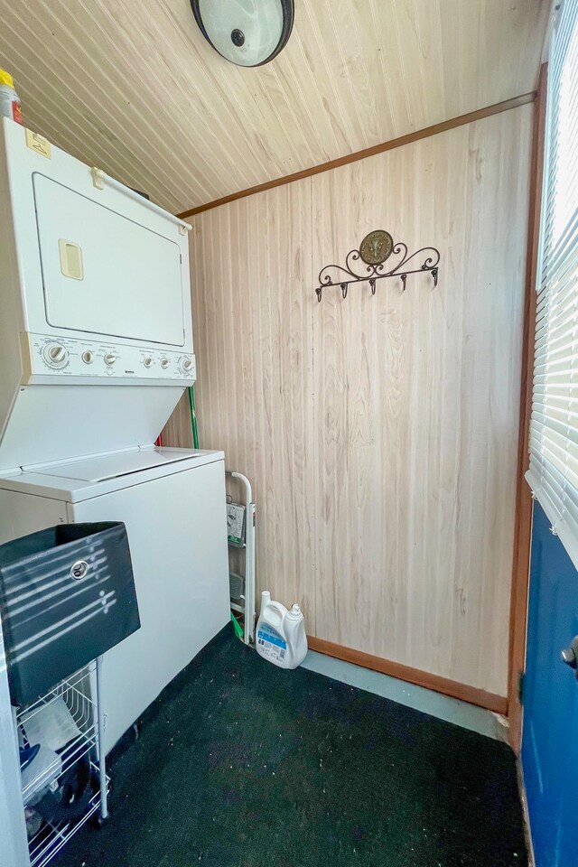 laundry area featuring wooden walls, wooden ceiling, stacked washing maching and dryer, and carpet floors