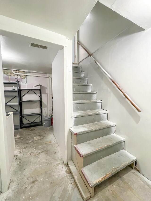 stairs featuring unfinished concrete flooring and visible vents