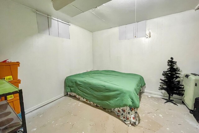 bedroom featuring concrete floors and baseboards