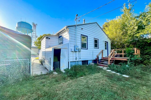 rear view of property featuring a wooden deck and fence