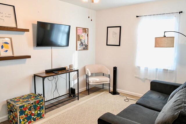 living room with baseboards and ceiling fan