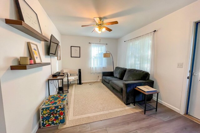 living area with light wood finished floors, baseboards, and ceiling fan