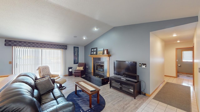 living room with light hardwood / wood-style floors, a fireplace, and vaulted ceiling