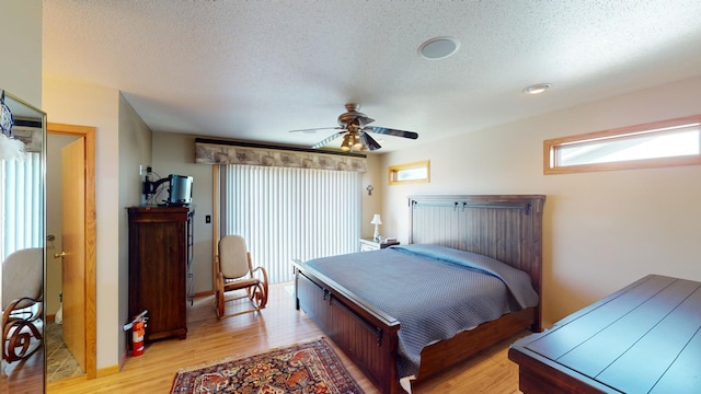 bedroom with light wood-type flooring, a textured ceiling, and ceiling fan