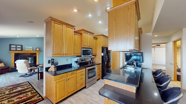 kitchen with lofted ceiling, sink, kitchen peninsula, light hardwood / wood-style flooring, and appliances with stainless steel finishes