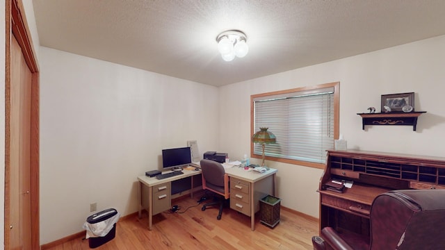 home office featuring light wood-type flooring and a textured ceiling