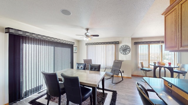 dining space with ceiling fan, a textured ceiling, and light wood-type flooring