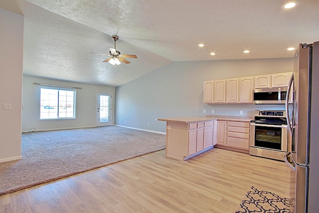 kitchen with ceiling fan, kitchen peninsula, light hardwood / wood-style floors, vaulted ceiling, and appliances with stainless steel finishes