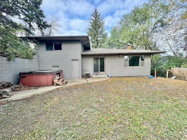 rear view of property with central AC, a yard, a patio area, and a hot tub