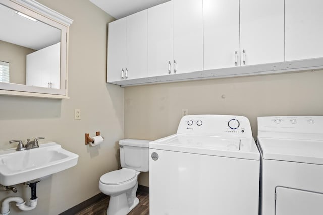 clothes washing area featuring washing machine and dryer, dark hardwood / wood-style flooring, and sink