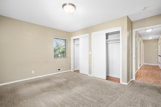 unfurnished bedroom with carpet flooring and multiple closets