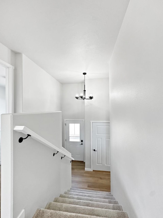 staircase with hardwood / wood-style flooring and a notable chandelier