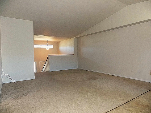 empty room featuring vaulted ceiling and carpet