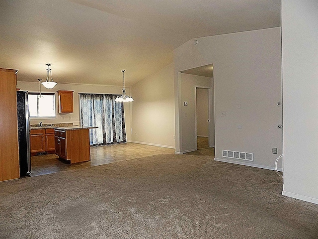 kitchen featuring a kitchen island, refrigerator, dark colored carpet, hanging light fixtures, and vaulted ceiling