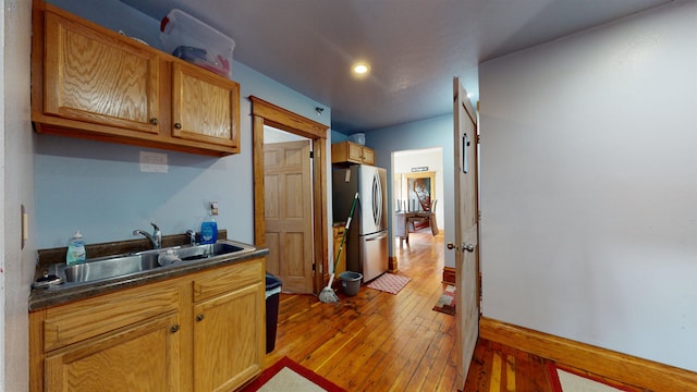 kitchen featuring light wood-type flooring, stainless steel fridge, and sink