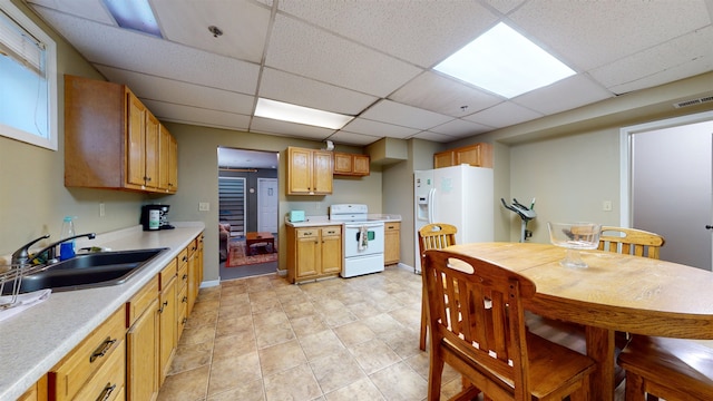 kitchen featuring light tile patterned floors, a paneled ceiling, sink, and white appliances