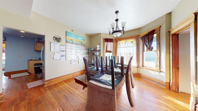 dining area with hardwood / wood-style floors and an inviting chandelier