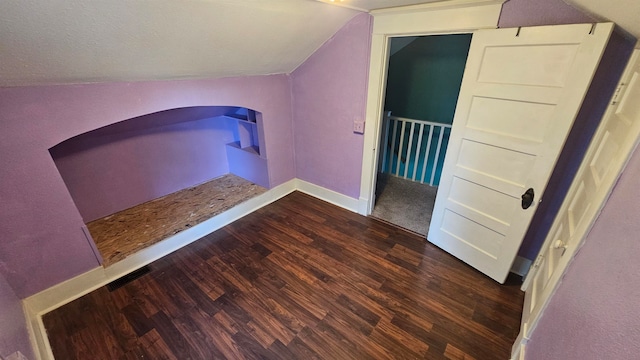 additional living space featuring vaulted ceiling and dark hardwood / wood-style flooring