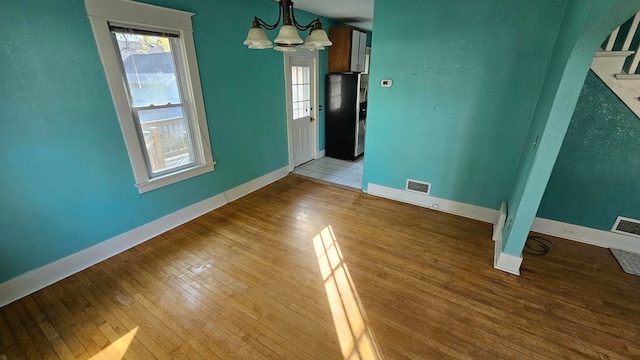 unfurnished dining area featuring light hardwood / wood-style floors and an inviting chandelier