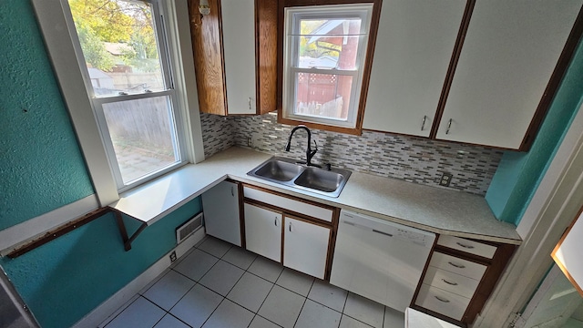 kitchen with backsplash, white dishwasher, sink, light tile patterned flooring, and white cabinetry