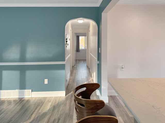 corridor with ornamental molding and light wood-type flooring