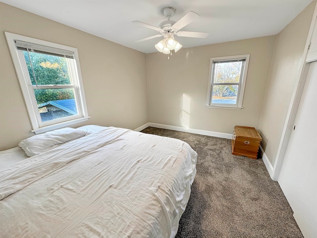 bedroom with dark carpet, multiple windows, and ceiling fan