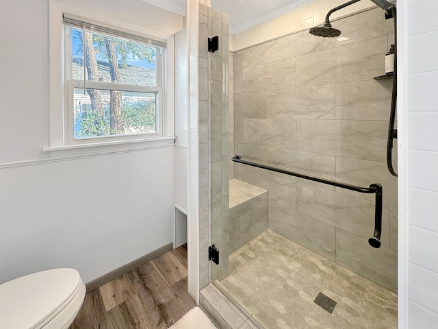 bathroom with toilet, ornamental molding, a shower with shower door, and wood-type flooring