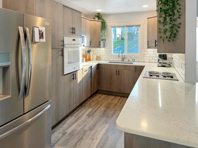 kitchen featuring backsplash, light brown cabinetry, sink, light hardwood / wood-style floors, and stainless steel appliances