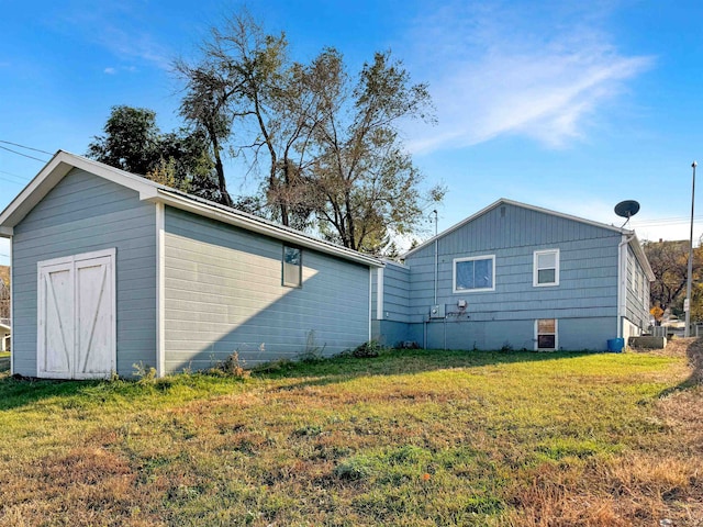 view of side of home featuring a storage unit and a lawn