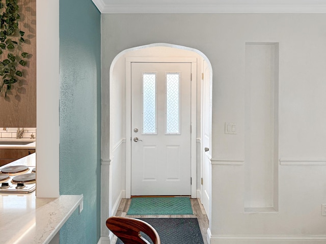 entrance foyer with ornamental molding, sink, and light wood-type flooring