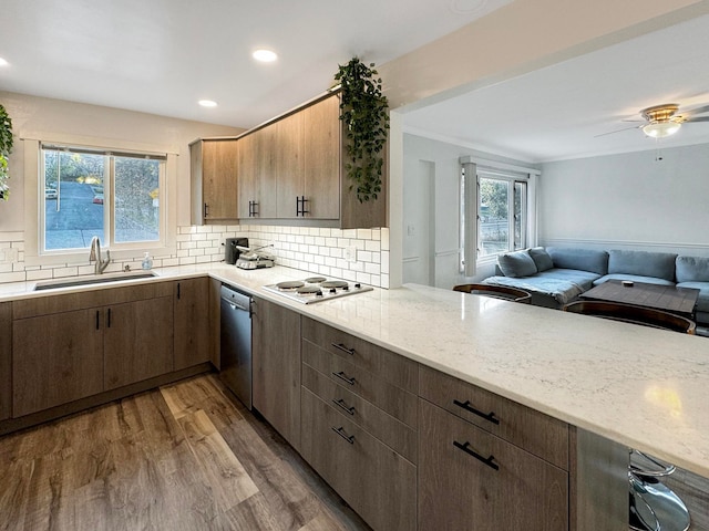 kitchen featuring white gas stovetop, decorative backsplash, sink, hardwood / wood-style floors, and stainless steel dishwasher