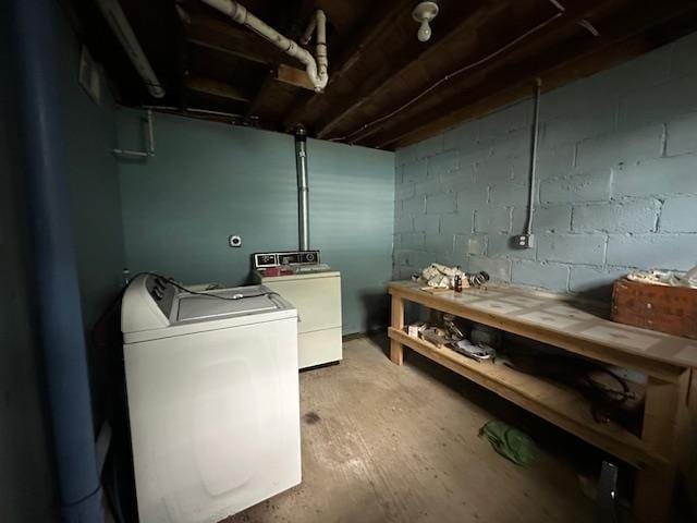 clothes washing area with washer and dryer, a workshop area, and wood-type flooring