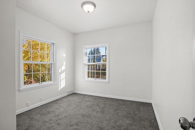 1012 4th St, Minot, ND 58701 - unfurnished room with baseboards, visible vents, and dark carpet
