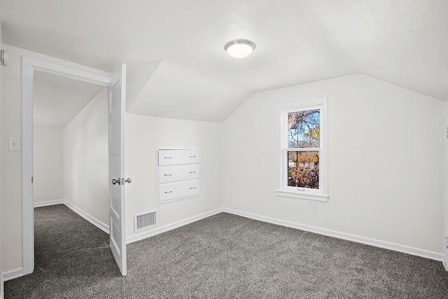 bonus room with dark colored carpet and vaulted ceiling