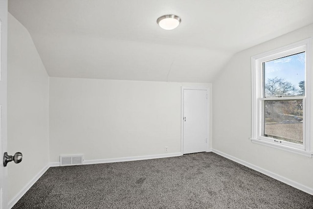 1012 4th St, Minot, ND 58701 - bonus room featuring vaulted ceiling, baseboards, visible vents, and dark carpet
