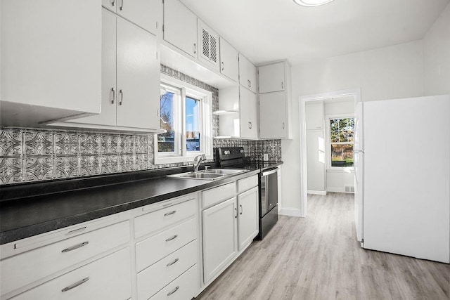 1012 4th St, Minot, ND 58701 - kitchen featuring a sink, freestanding refrigerator, a wealth of natural light, black range with electric stovetop, and dark countertops