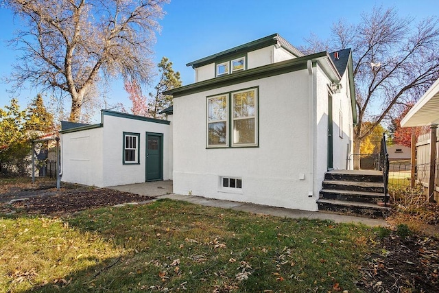1012 4th St, Minot, ND 58701 - rear view of property featuring stucco siding, fence, and a lawn