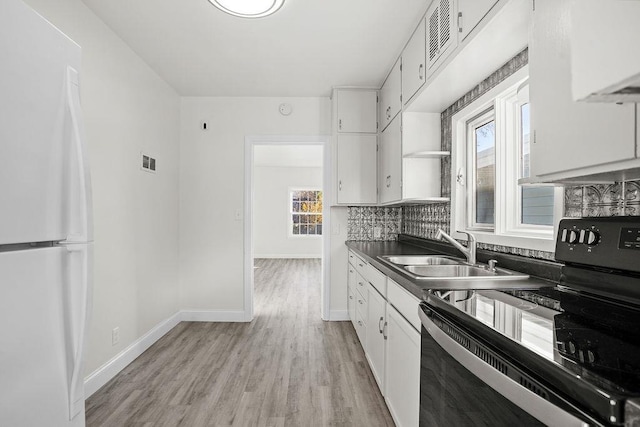 1012 4th St, Minot, ND 58701 - kitchen featuring freestanding refrigerator, a sink, white cabinetry, black range with electric cooktop, and dark countertops