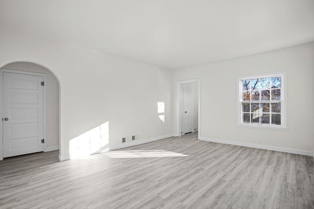 1012 4th St, Minot, ND 58701 - spare room with light wood-style flooring, baseboards, and arched walkways