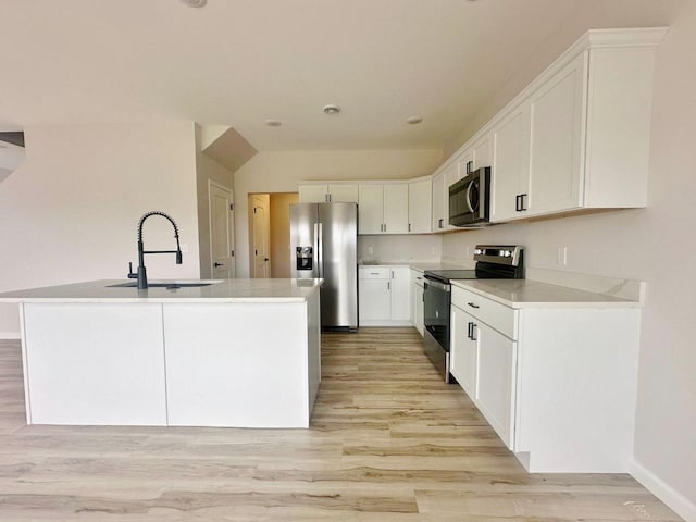 kitchen featuring appliances with stainless steel finishes, sink, light wood-type flooring, white cabinetry, and a kitchen island with sink