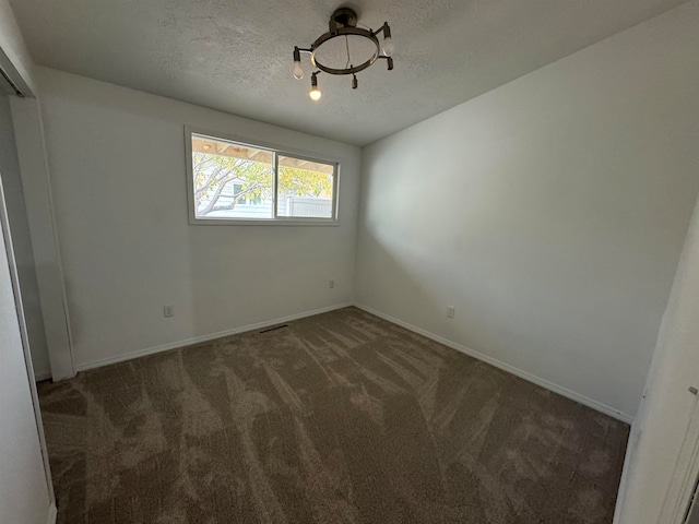 carpeted empty room featuring a textured ceiling