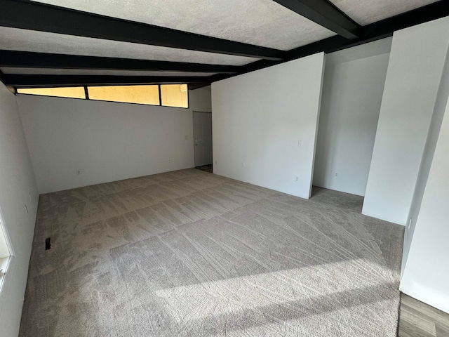 carpeted spare room with lofted ceiling with beams and a textured ceiling