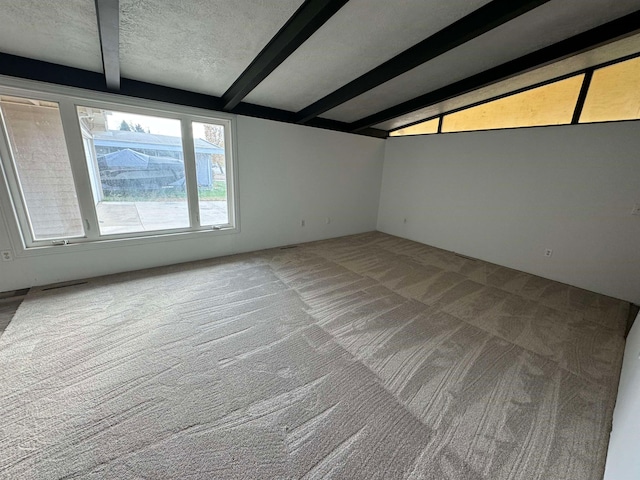 carpeted spare room featuring beamed ceiling and a textured ceiling