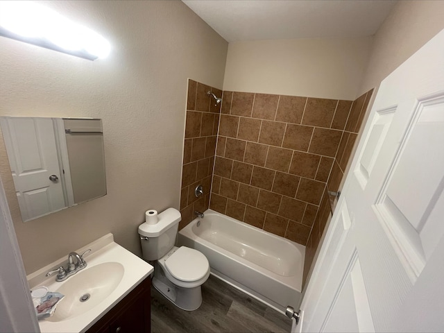 full bathroom with toilet, tiled shower / bath, hardwood / wood-style flooring, and vanity