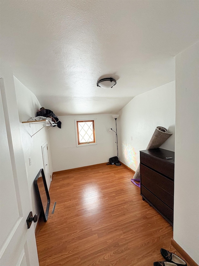 interior space with light wood-style floors, visible vents, a textured ceiling, and baseboards