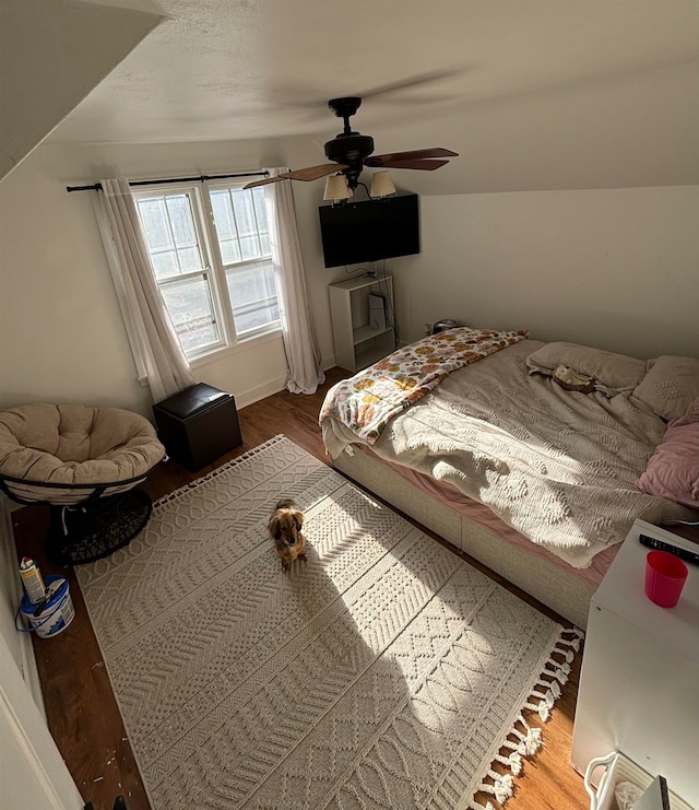 unfurnished bedroom featuring a ceiling fan, vaulted ceiling, and wood finished floors