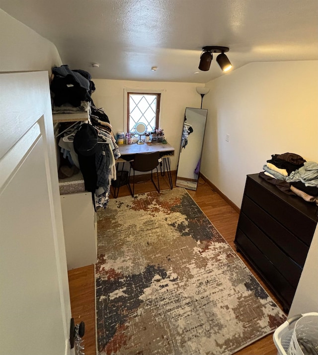 interior space with hardwood / wood-style floors, built in desk, and vaulted ceiling