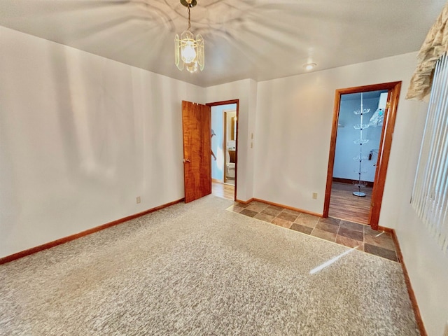 unfurnished room with a notable chandelier and carpet flooring